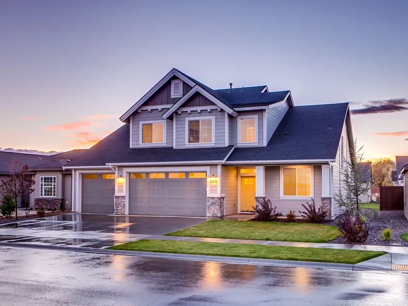 Home with a two-car garage at twilight after rain for emergency garage door service
