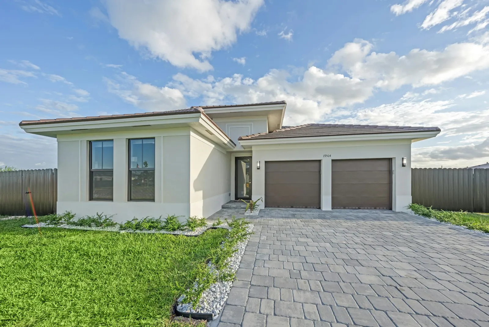 Single-story El Cajon home with two brown garage doors and a paver driveway