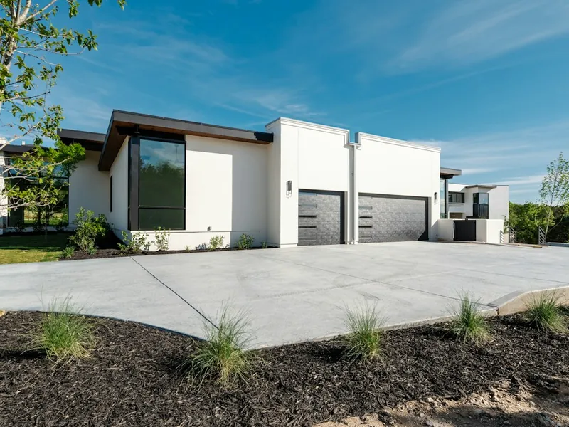 Modern white home with two dark garage doors and concrete driveway in El Cajon